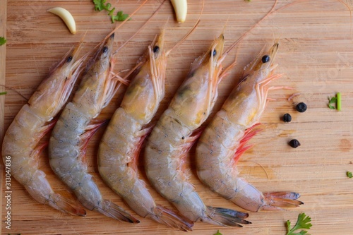 Fresh raw tiger prawns and spices on wooden Background