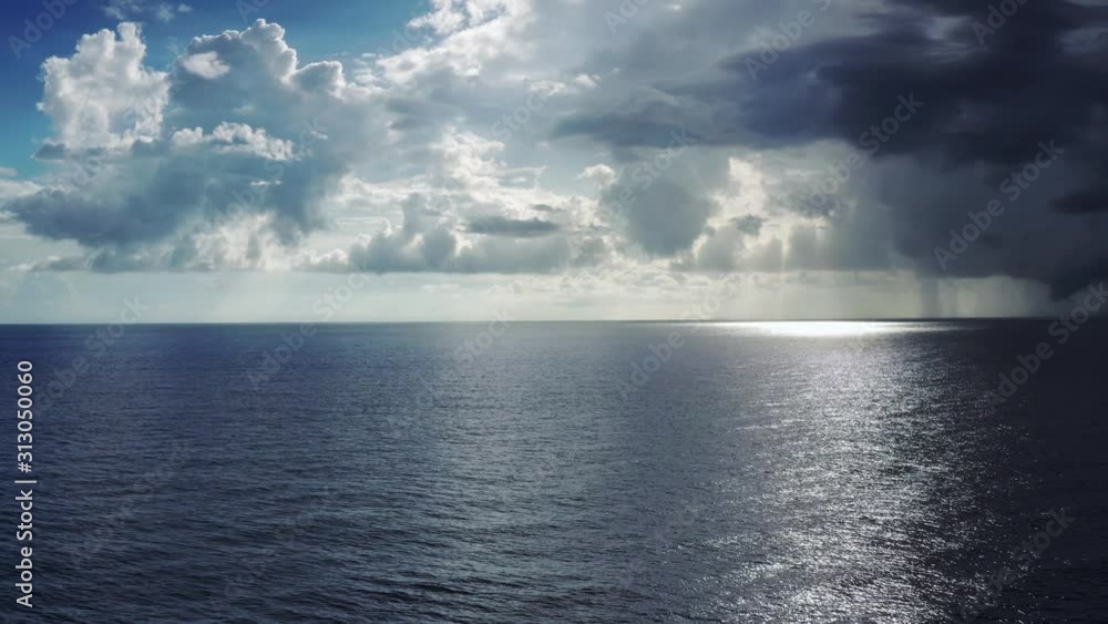 Aerial over ocean, slow descent, sun spot and rain on horizon, Roatan Aerial over ocean, slow descent, sun spot and rain on horizon, Roatan
