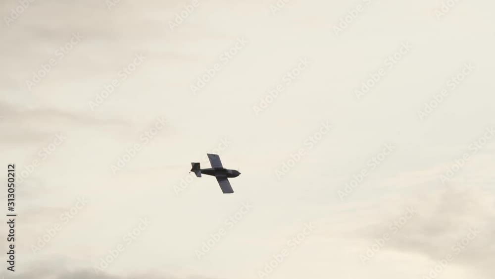A small homebuilt airplane is silhouetted against the bright sky as it rolls out from a turn in slow motion. A small homebuilt airplane is silhouetted against the bright sky as it rolls out from a turn in slow motion.