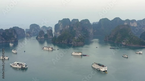 Cruise ships sitting on the top of the emerald waters of Ha LongBay, during the fog-filled morning photo