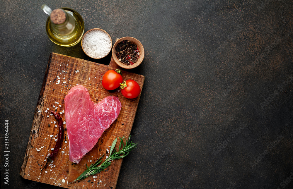 heart shaped raw beef steak on a cutting board with spices for valentines day on a stone background with copy space for your text, concept of cooking dinner for valentines day heart shaped raw beef steak on a cutting board with spices for valentines day on a stone background with copy space for your text, concept of cooking dinner for valentines day