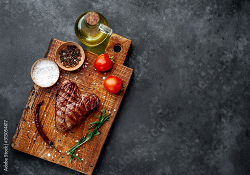 grilled beef steak with spices on a cutting board for Valentine's day on a stone background with copy space for your text