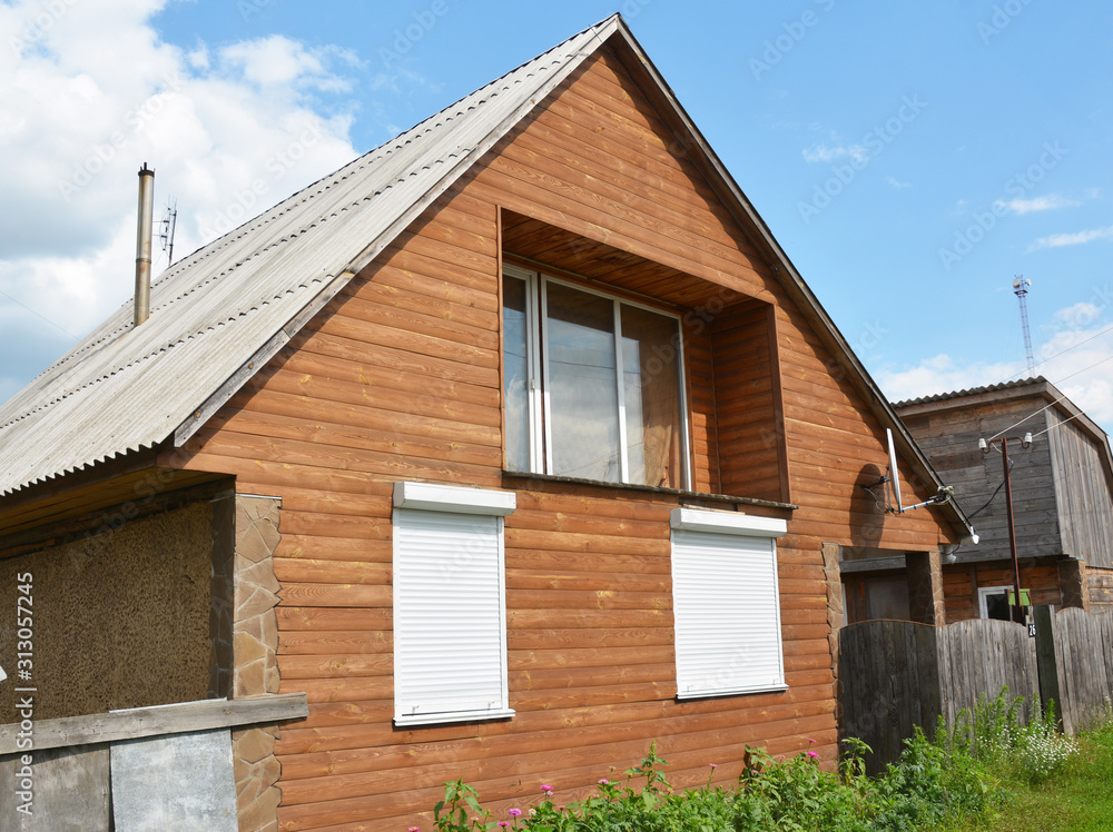 Wooden cottage with asbestos roof, balcony and rolling shutters  for window protection