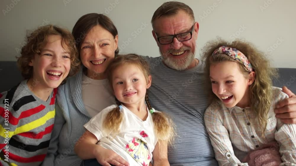 Grandchildren and their grandparents are sitting embraced on the couch. Happy family, grandparents and three grandchildren Grandchildren and their grandparents are sitting embraced on the couch. Happy family, grandparents and three grandchildren