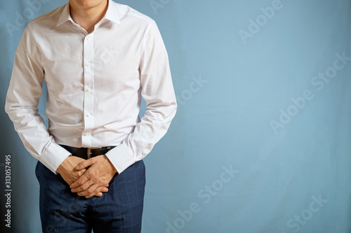 Tableau sur toile A man in trousers and a white shirt holds on to his groin, a symbol of testicula