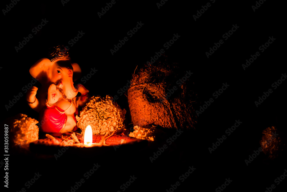 extreme low light photography of ganpati statue with shining diya and dry  coconut on black background. religious concept. Stock Photo | Adobe Stock