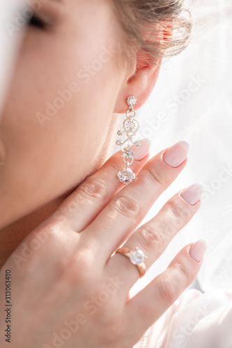 Blonde bride is wearing fashion jewelry on her wedding day. Morning bridal portrait