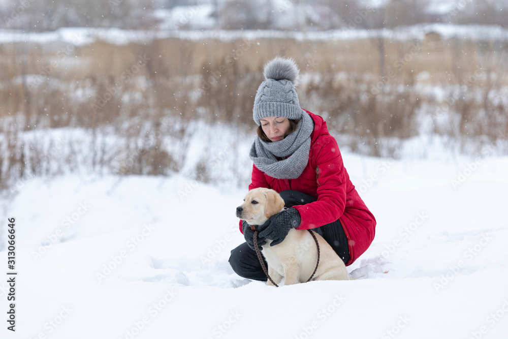 Beautiful young woman hugging her dog in snow Beautiful young woman hugging her dog in snow