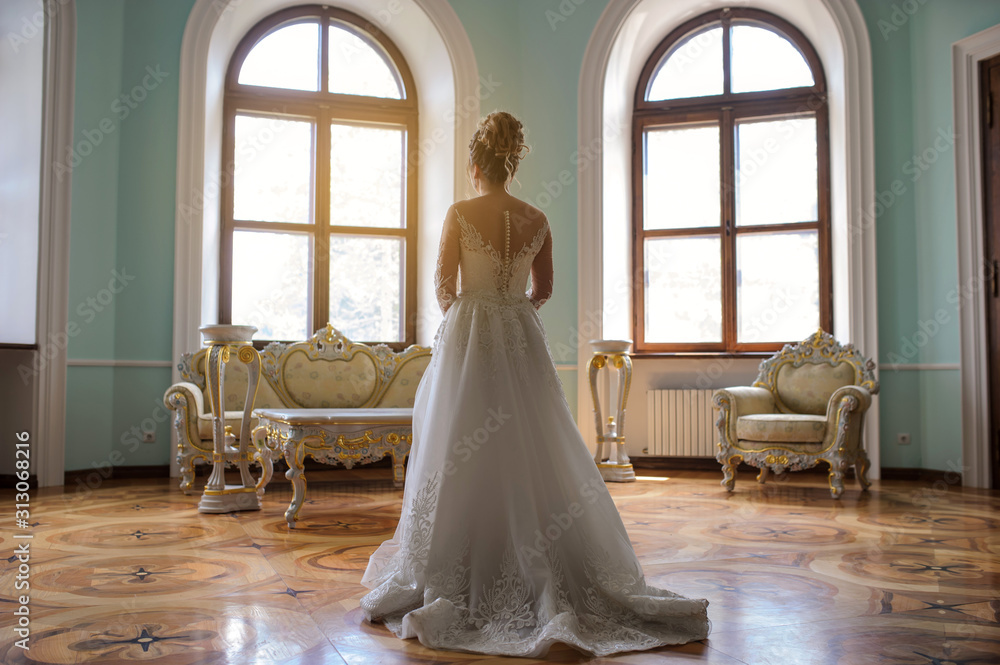 back view of a bride in a living room with furniture in royal style in a palace/castle back view of a bride in a living room with furniture in royal style in a palace/castle