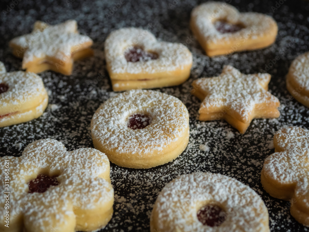 Homemade Linzer Christmas cookies. Biscuits with shortcrust pastry and strawberry jam on dark background.