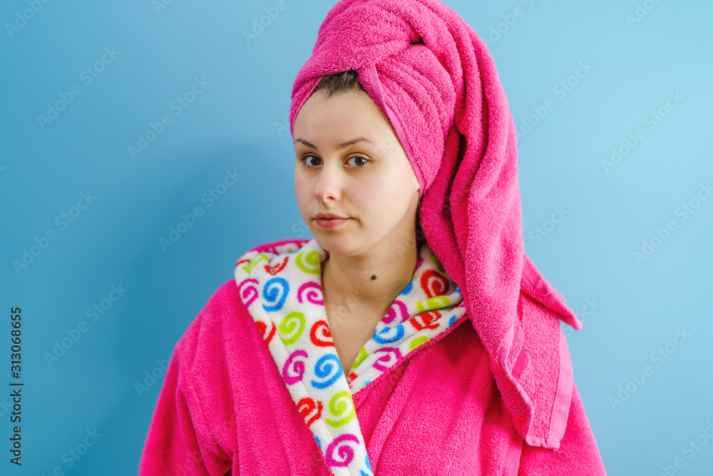 Portrait of young beautiful caucasian woman wearing bathrobe and pink towel on her hair head in front of the blue wall
