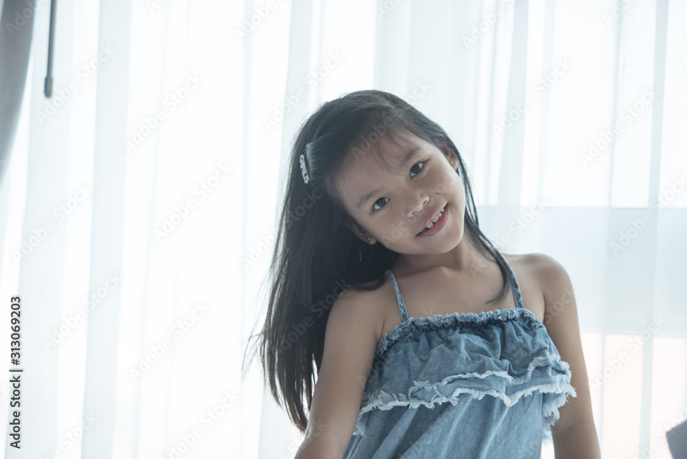 A bright, cute girl stood beside the bed in her bedroom. Beautiful little girl smiling. Portrait of cheerful kid lies at windowsill. A bright, cute girl stood beside the bed in her bedroom. Beautiful little girl smiling. Portrait of cheerful kid lies at windowsill.