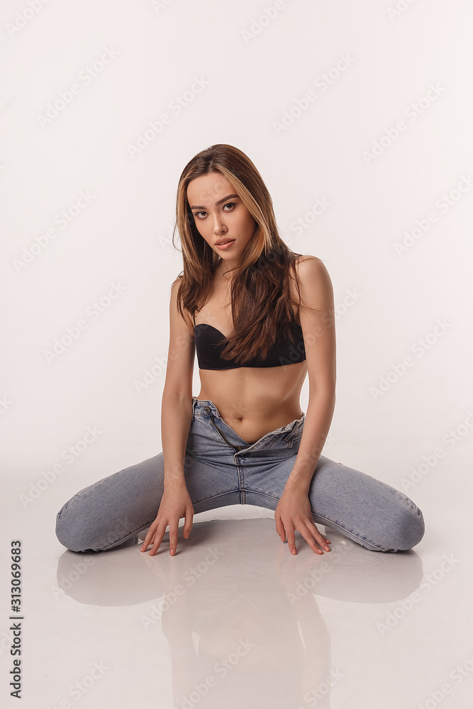 portrait of sexy asian woman with long hair posing in black lingerie and  blue jeans on