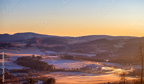 sunrise in the mountains - winter hilly landscape with forests, trees and meadows (with hoarfrost and snow)