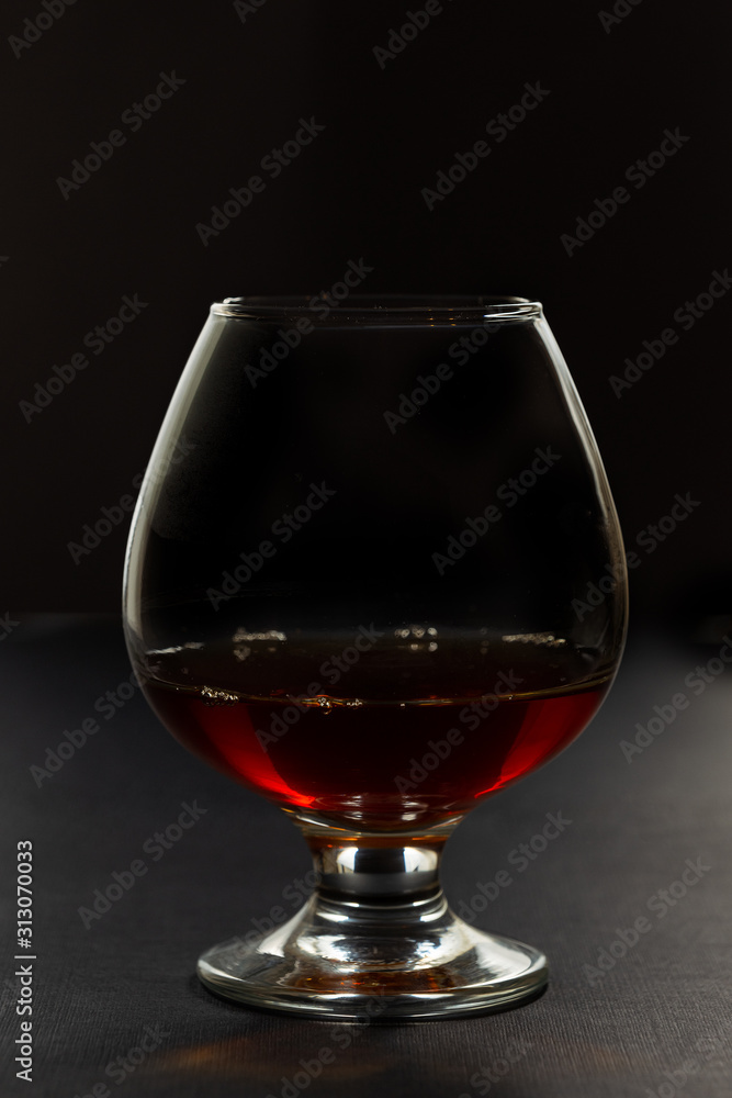 Cognac in a glass, in a dark vein, in backlight Cognac in a glass, in a dark vein, in backlight