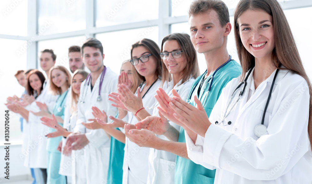 group of smiling young doctors applauds standing in a row