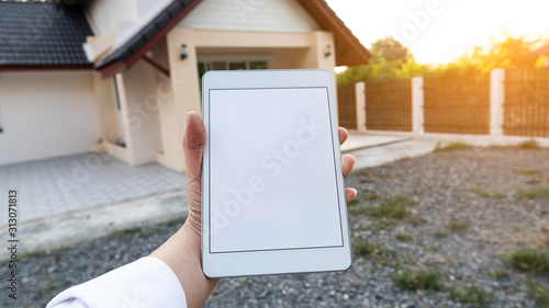 The tablet in the hand has a white screen, home background and orange light.