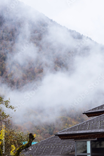 Fog in the mountains against the background of peaks with snow in the fall in Sochi, Russia.