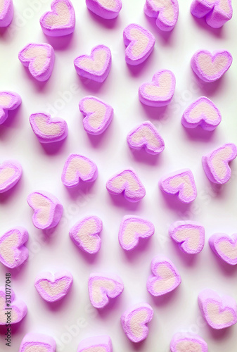 Vertical Image of Purple Pink Heart Shaped Marshmallow Candies Scattered on White Background