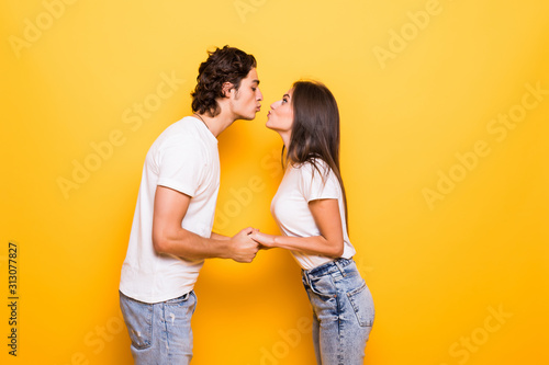 Young couple in love kiss isolated yellow background