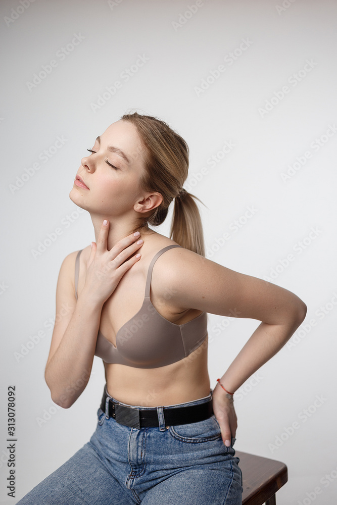 portrait of sexy cacasian woman with long hair posing in beige lingerie and blue jeans on white studio background. model tests of pretty girl in bra. attractive female sits on stool portrait of sexy cacasian woman with long hair posing in beige lingerie and blue jeans on white studio background. model tests of pretty girl in bra. attractive female sits on stool
