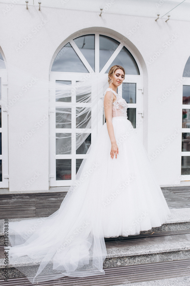 Fototapeta premium Wedding fashion blondie caucasian girl in beautiful dress outdoors in old city background. Beauty, wedding, fashion concept