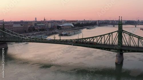 4k Aerial shot of Yellow Tram crossing Danube river on Liberty Bridge at dawn in Budapest, Hungary