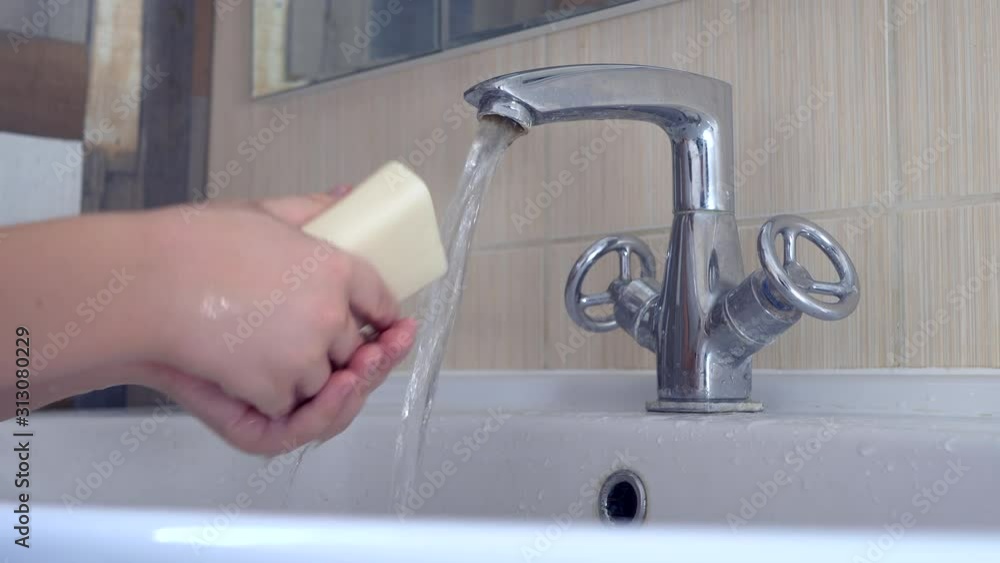 Happy boy washes hands with soap. Child playing with bar of soap and water in sunny bathroom with window. Water activities for children. Hygiene and skin care for children. Bathroom interior Happy boy washes hands with soap. Child playing with bar of soap and water in sunny bathroom with window. Water activities for children. Hygiene and skin care for children. Bathroom interior