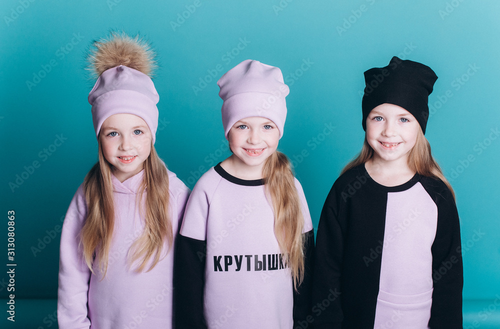 Happy cute adorable triplets girls posing in studio together on isolated blue background. Childhood, children, twins concept. Smiling girls playing together Happy cute adorable triplets girls posing in studio together on isolated blue background. Childhood, children, twins concept. Smiling girls playing together