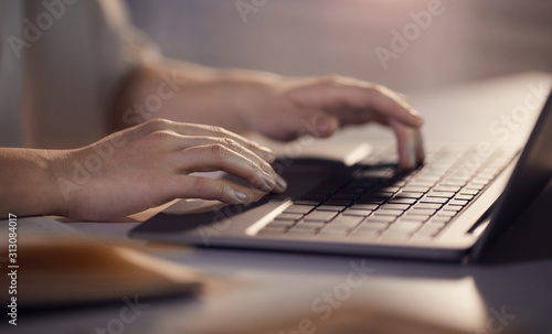 Close-up of woman sitting at the table and typing on computer keyboard she working online