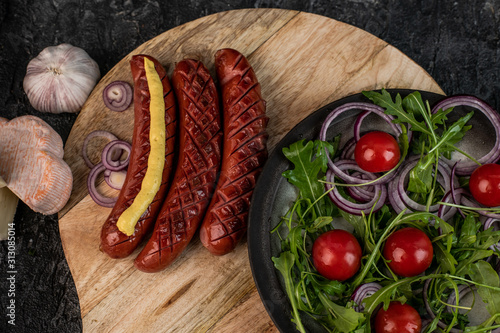 roasted sausages with mustard and onion, next to rocket salad and cherry tomatoes