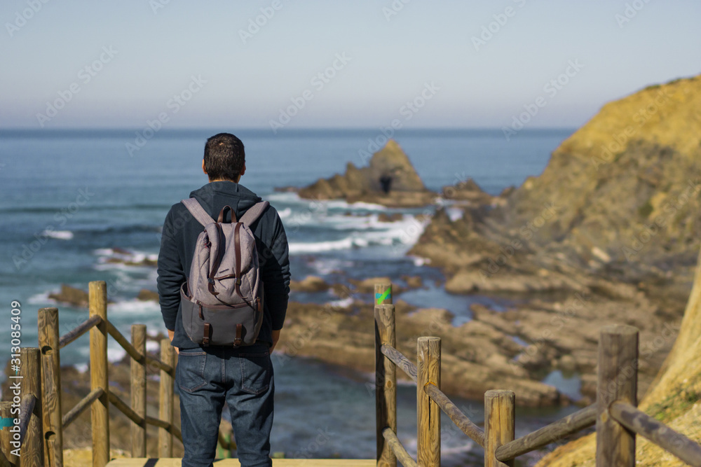Man with a backpack seeing Praia dos Machados beach in Costa Vicentina, Portugal Man with a backpack seeing Praia dos Machados beach in Costa Vicentina, Portugal