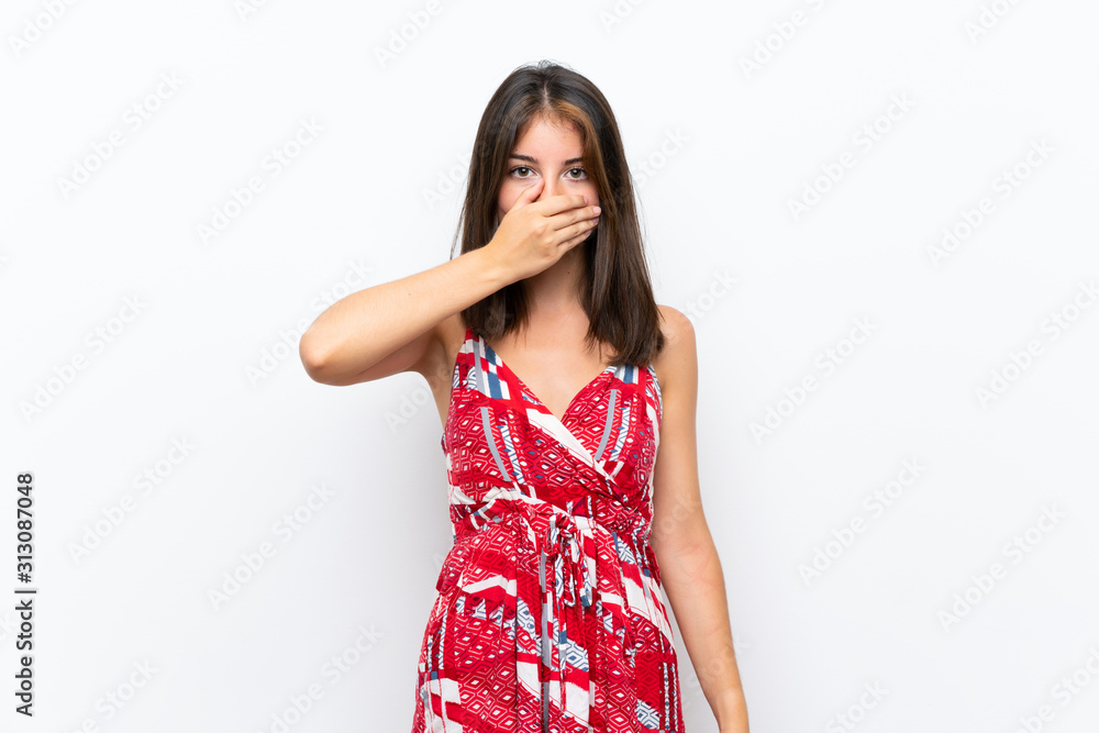 Caucasian girl in red dress over isolated white wall covering mouth with hands Caucasian girl in red dress over isolated white wall covering mouth with hands