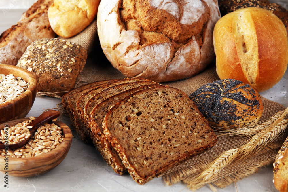 Assortment of baked bread and bread rolls and cutted bread on table background