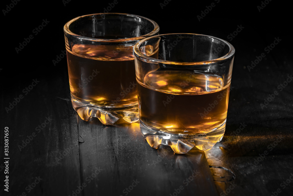 two glasses of cognac on a black tree