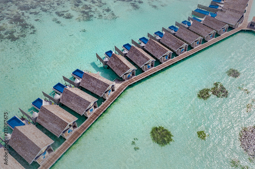Amazing bird eyes view in Maldives resort with private pools and long jetty over beautiful turquoise sea water. Aerial Maldives island