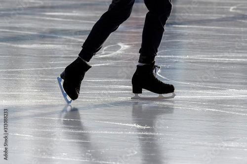 Legs of a man skating on an ice rink. Hobbies and sports. Vacations and winter activities. © photosaint