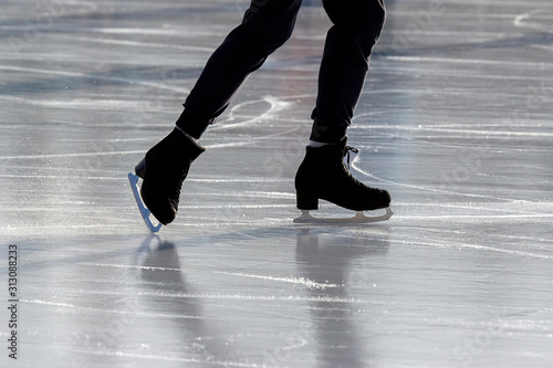 Legs of a man skating on an ice rink. Hobbies and sports. Vacations and winter activities.