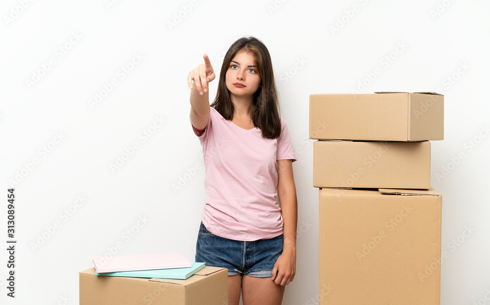 Young girl moving in new home among boxes touching on transparent screen Young girl moving in new home among boxes touching on transparent screen