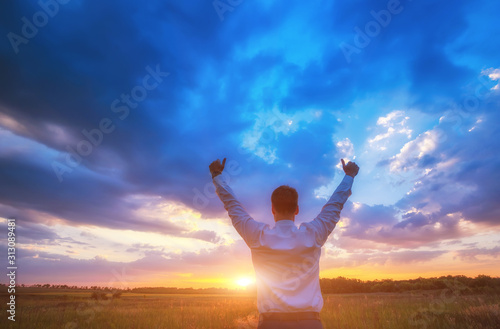 happy businessman, standing in field over wind background with his hands up and thumbs up