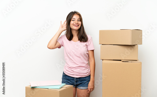 Young girl moving in new home among boxes listening something