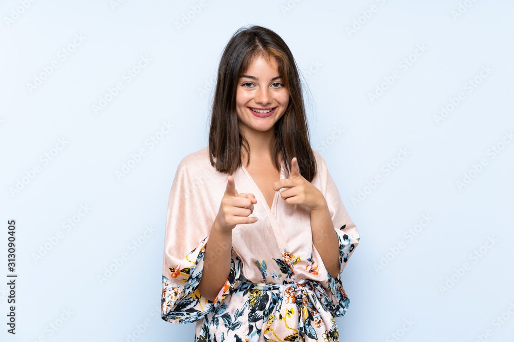Caucasian girl with kimono over isolated blue background points finger at you Caucasian girl with kimono over isolated blue background points finger at you