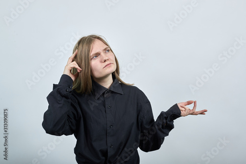 Serious charming caucasian young woman in fashion black shirt keeping finger on gead, spread hand, thinking isolated on gray background in studio. People sincere emotions, lifestyle concept. photo