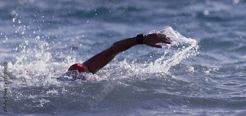 Man swimmer swimming crawl in blue sea, training for triathlon