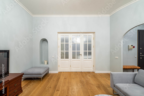 Living room with furniture in apartment. Modern interior in light tones. Wall with white door.