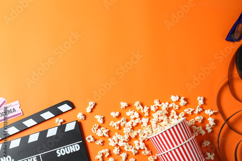 Flat lay composition with clapperboard and cinema tickets on orange background, space for text