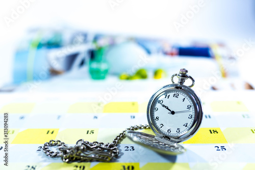 Old pocket watch on calendar, shallow depth of field, copy space, conceptual image of passing time. © Alpar