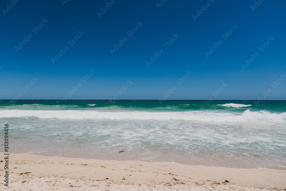 view of Scarborough beach, one of the most popular beaches near Perth on the Indian Ocean, with intense turquoise water and ships in the distance