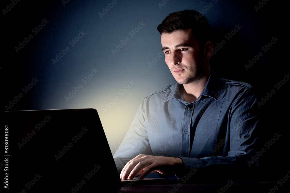 Young handsome businessman working late at night in the office with a dark background Young handsome businessman working late at night in the office with a dark background