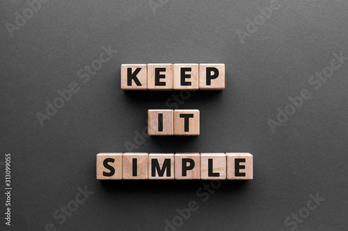 Keep it simple - word from wooden blocks with letters, to make something easy, keep it simple concept, gray background